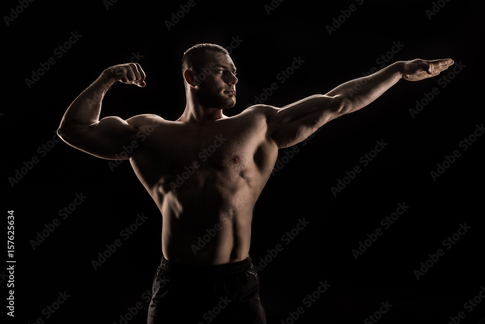 young caucasian shirtless athlete flexing muscles and looking away