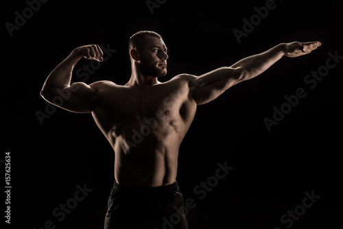 young caucasian shirtless athlete flexing muscles and looking away