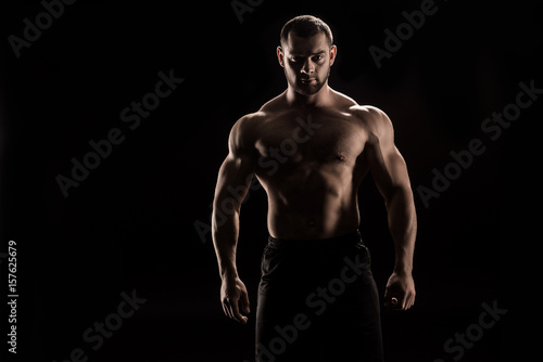 young confident shirtless athlete standing and looking at camera