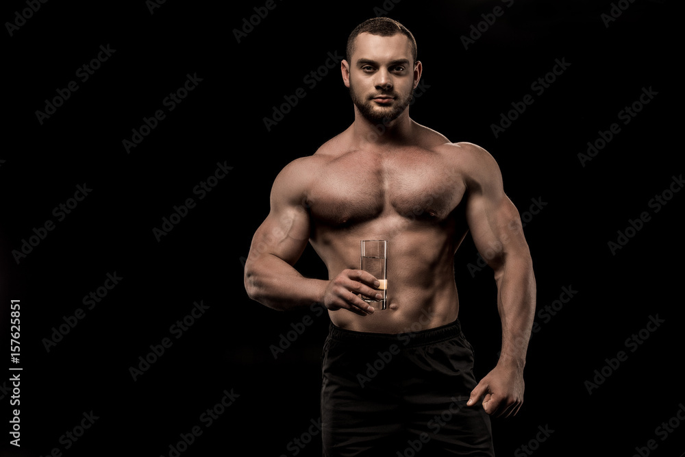 shirtless man holding glass of water in hand isolated on black