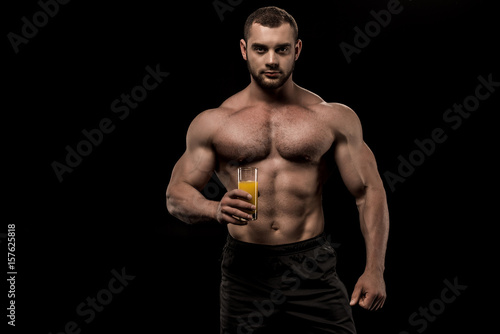 sportive man holding glass of fresh juice in hand isolated on black