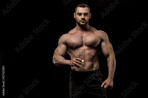 shirtless man holding glass of water in hand isolated on black