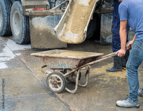 Controlled Low Strength Material (CLSM) pouring down from mixer truck to a trolley and workers still working