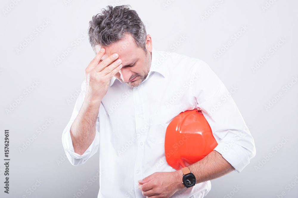 Portrait of architect holding hardhat making tired gesture Portrait of architect holding hardhat making tired gesture