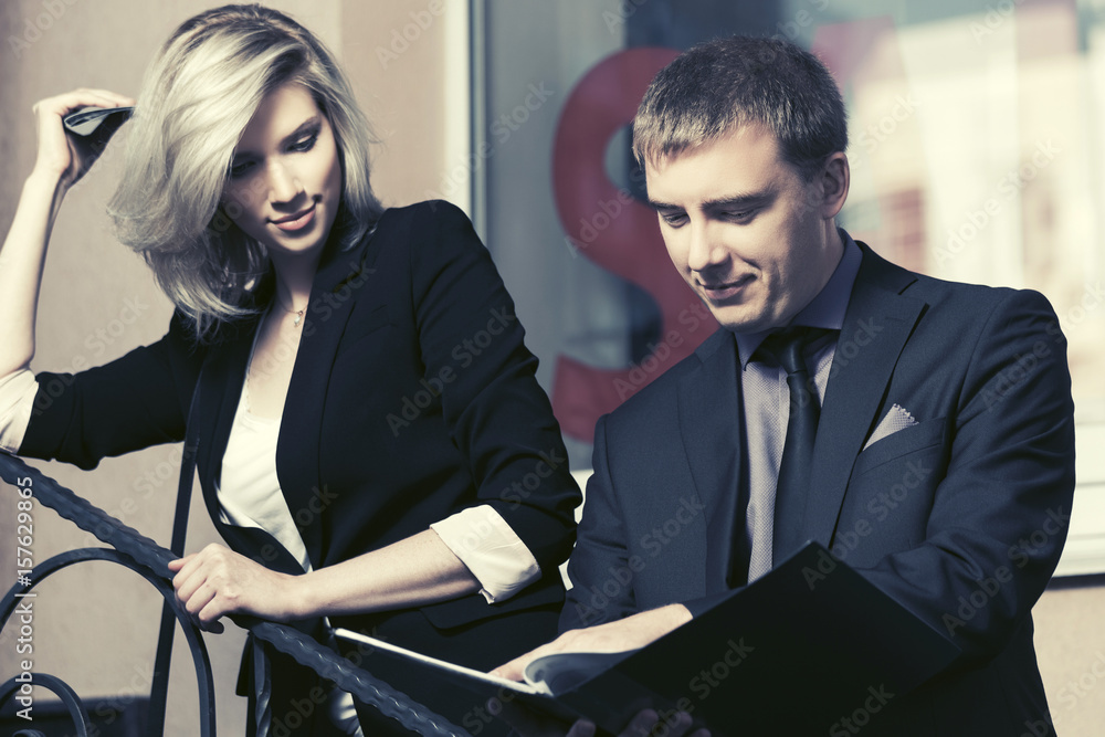 Fototapeta premium Young business couple with a folder against office window