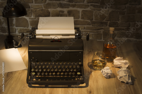 Classic Typewriter in cliche scenario with whiskey photo