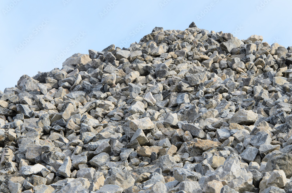 Pile of gray gravel stones with blue sky and clouds background Pile of gray gravel stones with blue sky and clouds background