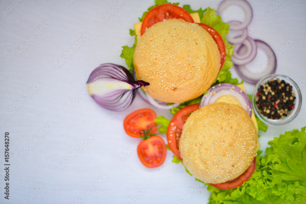 Hamburger with cheese, meat, tomatoes and onions and herbs. On Wooden background. Top view. Free space. Hamburger with cheese, meat, tomatoes and onions and herbs. On Wooden background. Top view. Free space.