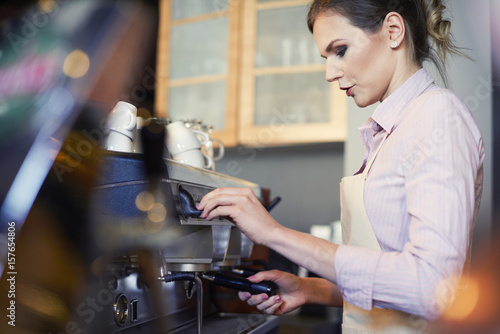 Female barista preparing coffee in cafe .