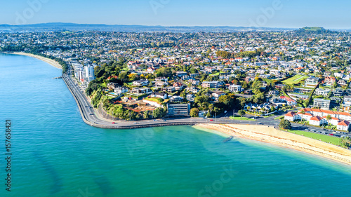 Aerial view on a road running along sea shore with residential suburbs on the background. Auckland, New Zealand.