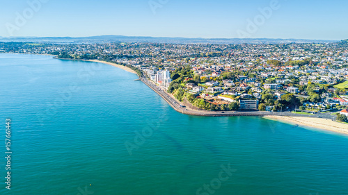 Aerial view on a road running along sea shore with residential suburbs on the background. Auckland  New Zealand.