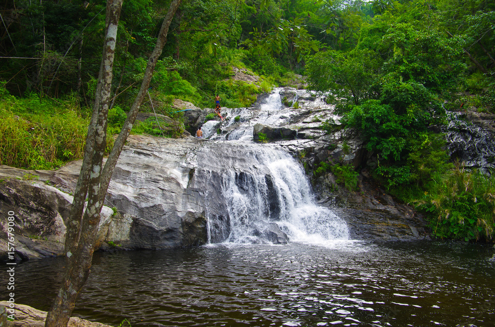 Fototapeta premium KHLONG LAN, THAILAND - August, 2016: Jungle landscape with flowing water of Khlong Nam Lai waterfall in Kamphaeng Phet province at deep tropical rain forest. Khlong Lan National Park, Thailand