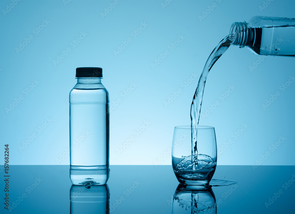 Bottle with creative splashing water in the glass Bottle with creative splashing water in the glass