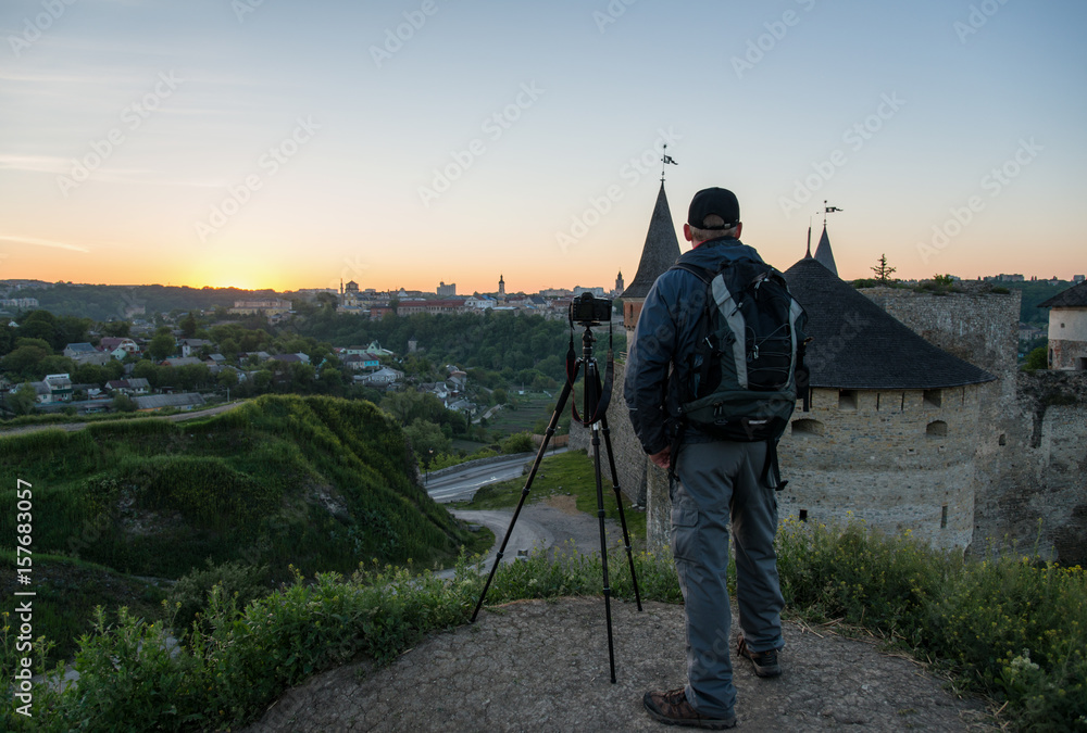Photographer with camera at sunrise in front of ancient castle