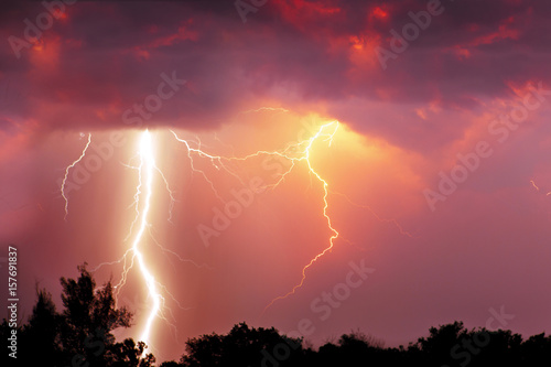 Fork lightning over dark orange sky on stormy day