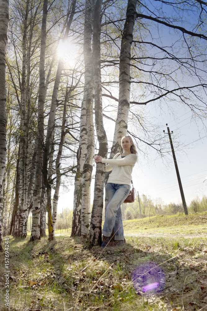 The young woman near a birch in park in the early spring The young woman near a birch in park in the early spring
