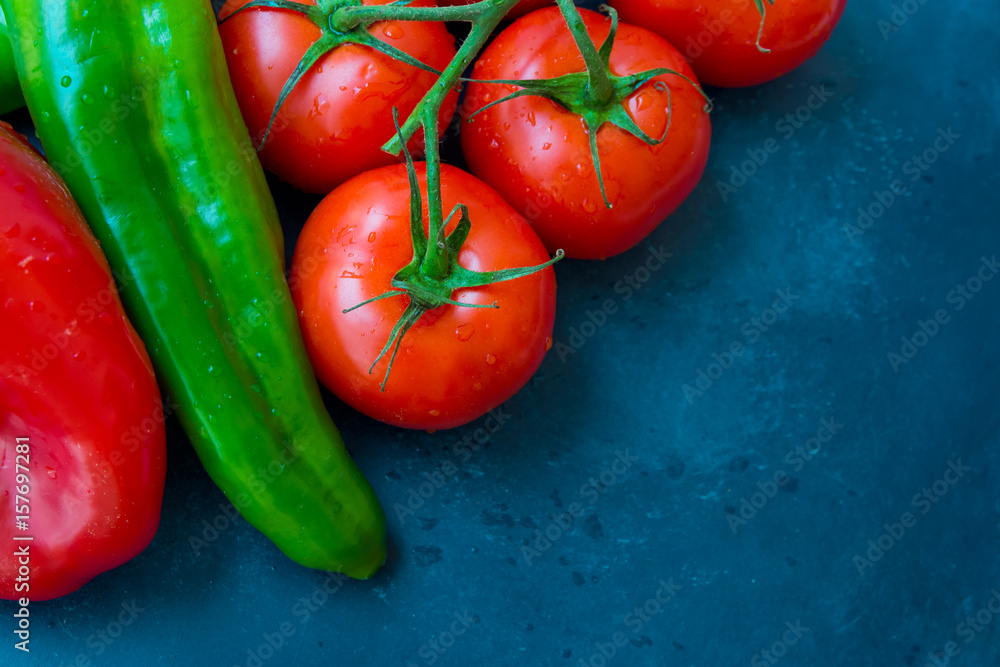 Fresh organic vegetables, tomatoes on a vine, green italian and red bell peppers, dark blue background, styled image, top view Fresh organic vegetables, tomatoes on a vine, green italian and red bell peppers, dark blue background, styled image, top view