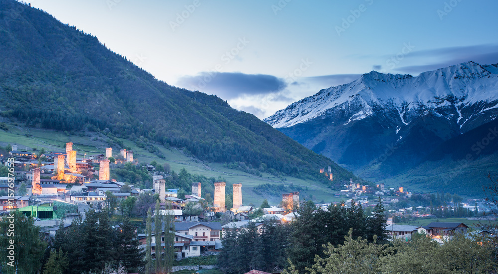 View of the Svanetian towers  in Mestia village against snowy mountains at sunrise. Upper Svaneti, Georgia