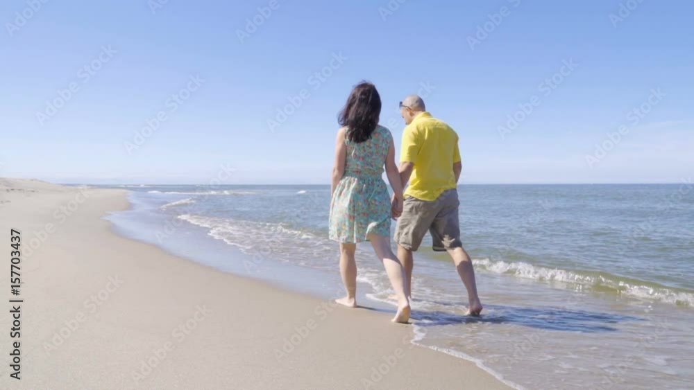 Happy couple walk along the seacoast barefoot Beach with white sand. Slow Motion. Happy couple walk along the seacoast barefoot Beach with white sand. Slow Motion.