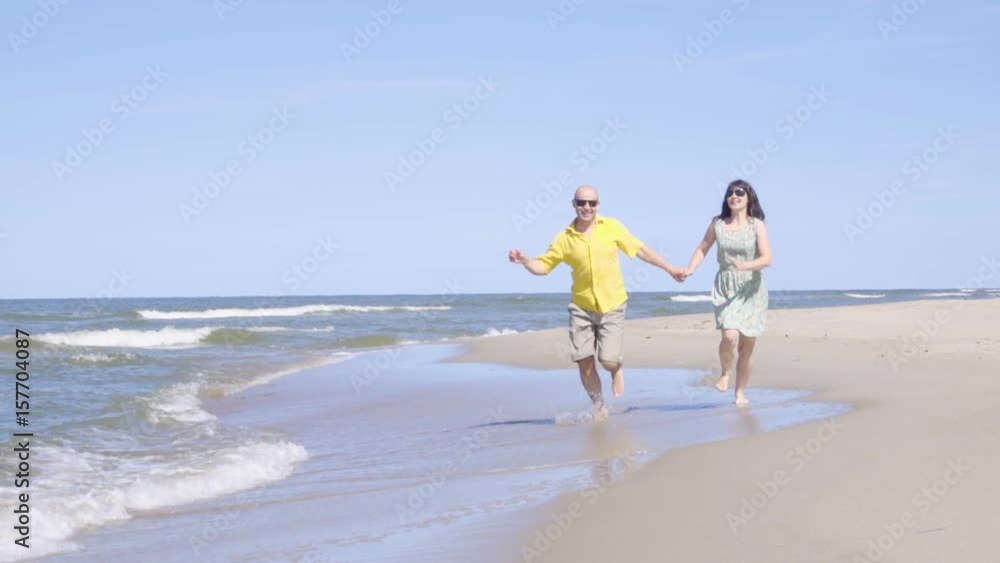 Happy couple walk along the seacoast barefoot Beach with white sand. Slow Motion. Happy couple walk along the seacoast barefoot Beach with white sand. Slow Motion.