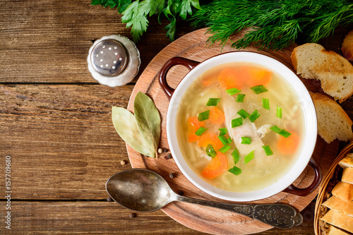 Obraz na plátně Homemade chicken soup with noodles and vegetables in ceramic bowl on wooden table