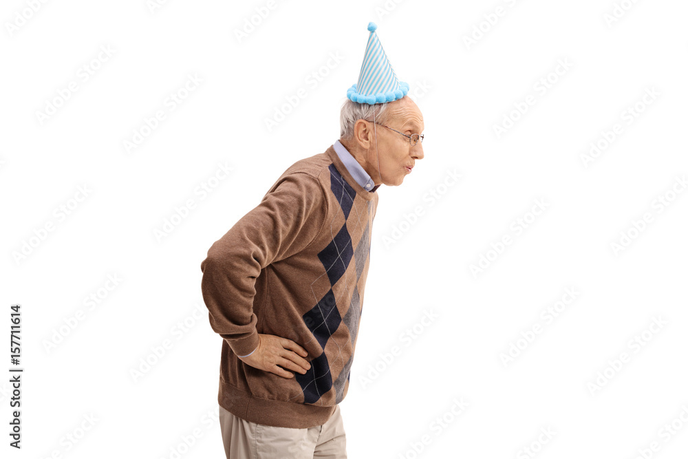 Elderly man with a party hat blowing with his mouth Elderly man with a party hat blowing with his mouth