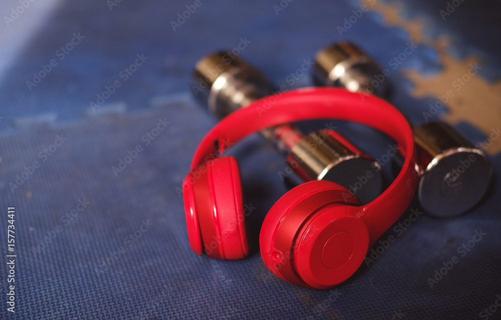 Red headphone and dumbbell on blue ground in gym. fitness concept music relax for fitness Red headphone and dumbbell on blue ground in gym. fitness concept music relax for fitness