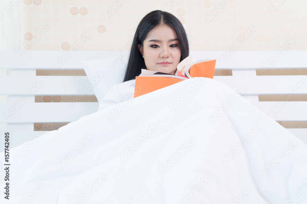 Woman lying in bed while reading a book Woman lying in bed while reading a book