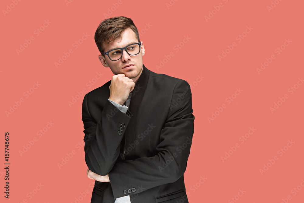 Young handsome man in black suit and glasses isolated on red background Young handsome man in black suit and glasses isolated on red background
