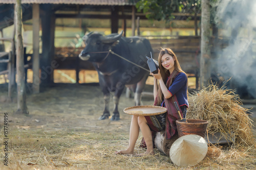 Thailand beautiful country woman listening radio with farm and buffalo background