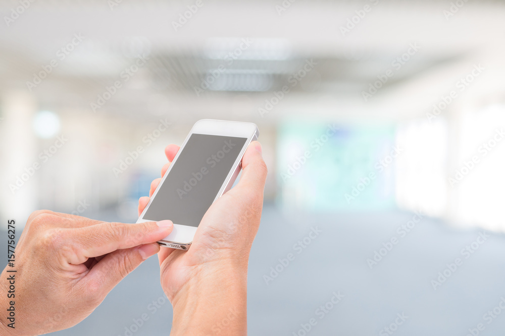 Hands holding mobile phone with blurred image of shopping mall Hands holding mobile phone with blurred image of shopping mall