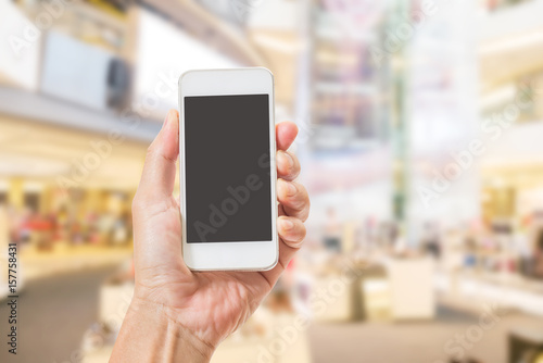 Hands holding mobile phone with blurred image of shopping mall