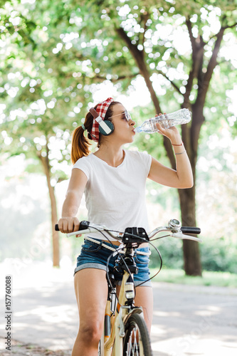 Young woman drinking water sitting on the bicycle