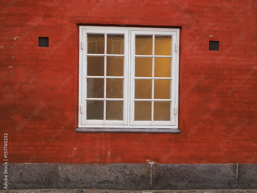 A red wall with a white window.