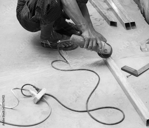 WORKER CUTTING STEEL WITH ELECTRIC WHEEL GRINDER