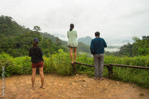 Group of tourist standing on the view point see tree forest and fog on the mountain background