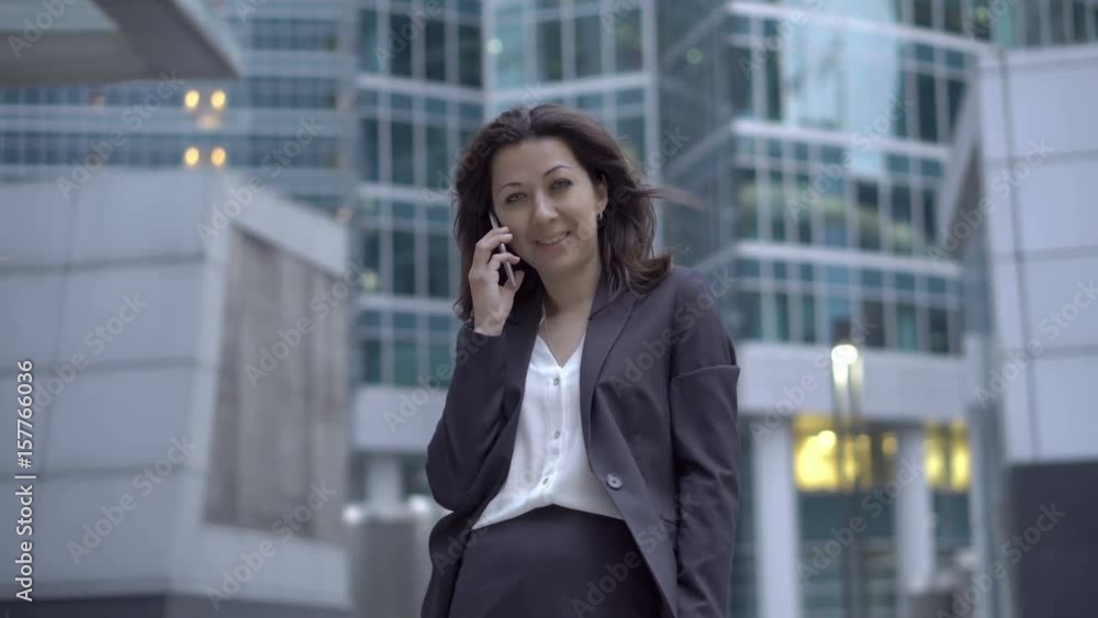 An employee of the stock market office is standing on the background of the business center where she is earning money and calling the cell phone, UHD 4K An employee of the stock market office is standing on the background of the business center where she is earning money and calling the cell phone, UHD 4K