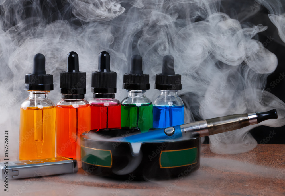 Electronic cigarette on ashtray cigarette lighter and bottles