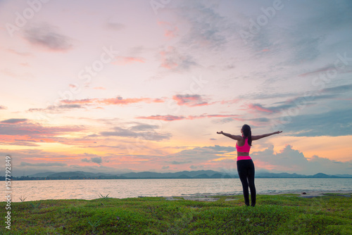 Healthy woman doing Yoga meditation exercises on the beach in sunset time, Thailand.