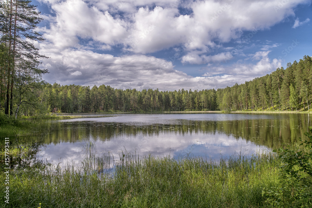 Beautiful circular lake in the Punkaharju area, Finland, surrounded by greenery, against a dramatic sky