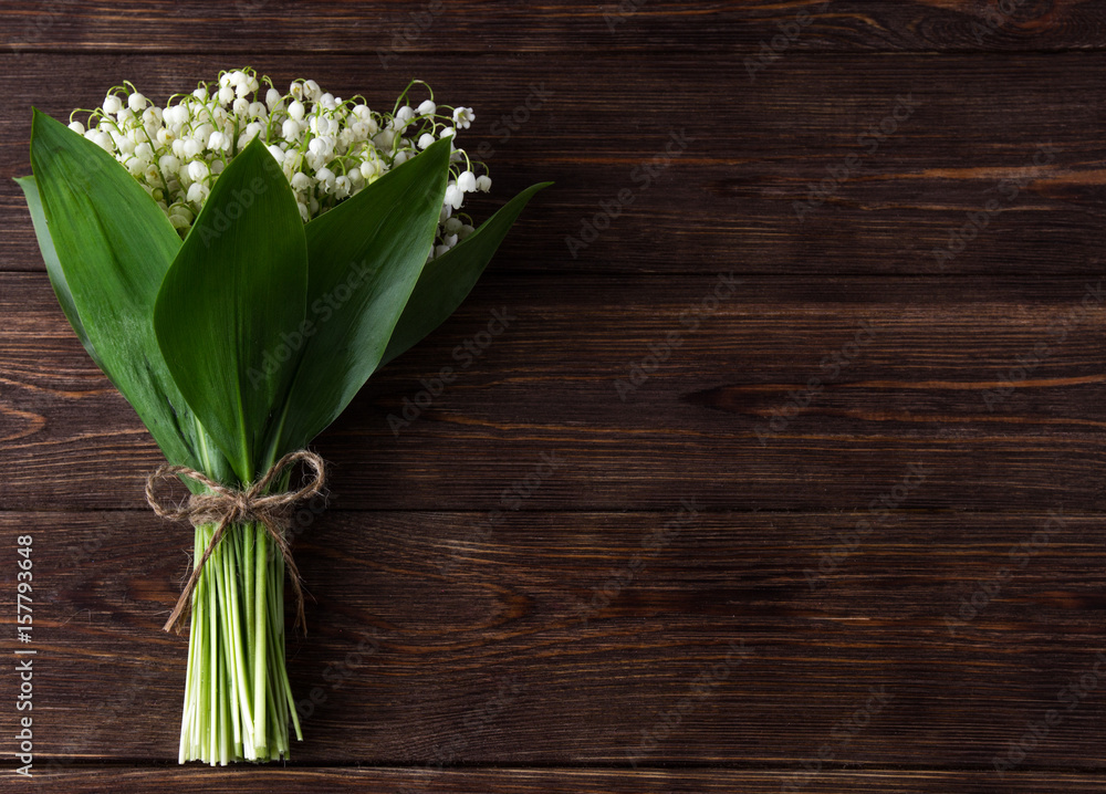 Lily of the valley on dark wooden background. Lily of the valley bouquet. Space for text.