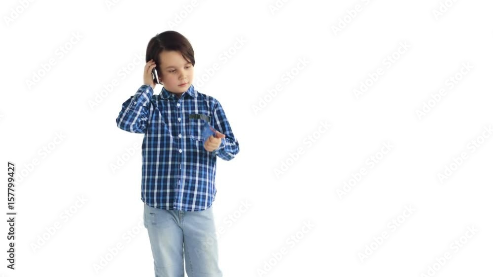 Serious little boy standing and using smartphone and credit card over white background Serious little boy standing and using smartphone and credit card over white background