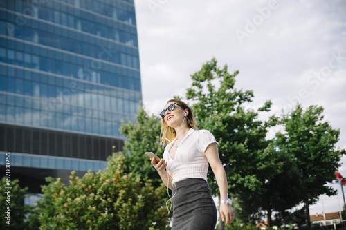 Young blond woman listening to music outdoors
