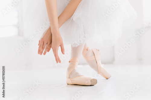 Young ballerina dancing, closeup on legs and shoes, standing in pointe position.
