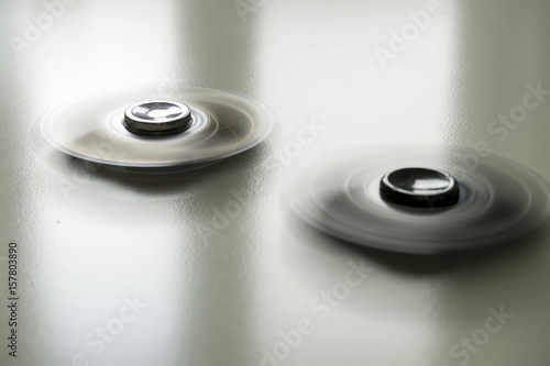 Long exposure with motion blur of two fidget spinners during fast rotation on an abstract background.