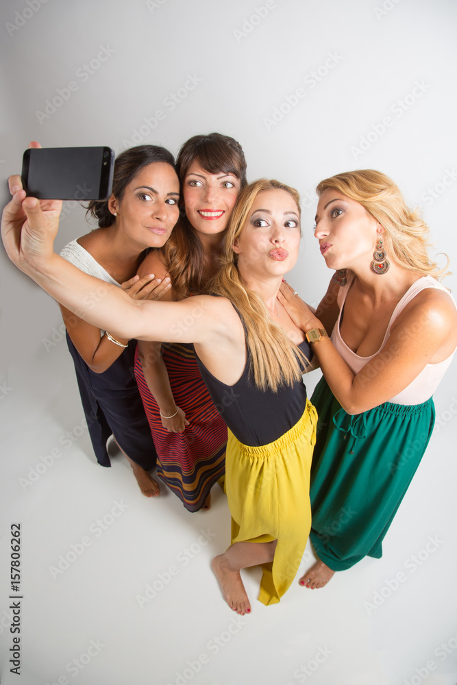 4 belle ragazze vestite con colori sgargianti, si fa un selfie dall'alto su  sfondo chiaro Photos | Adobe Stock