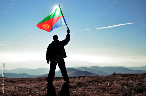 Photography Successful silhouette man winner waving Eritrea flag on top of the mountain peak