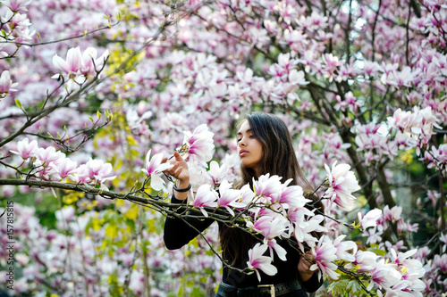 girl with long, brunette hair posing at magnolia tree