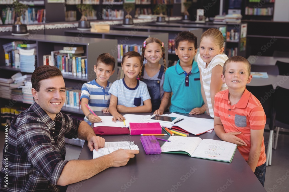 Portrait of happy teacher and schoolkids studying in library Portrait of happy teacher and schoolkids studying in library