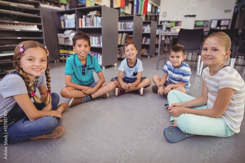 Portrait of happy schoolkids sitting in library
